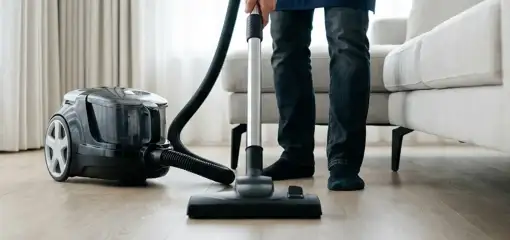 Professional house cleaner vacuuming a living room floor with a canister vacuum cleaner, Memphis, TN.