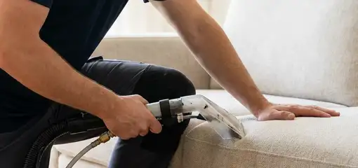 Professional upholstery cleaner deep-cleaning a fabric sofa with a handheld extraction tool, Memphis, TN.